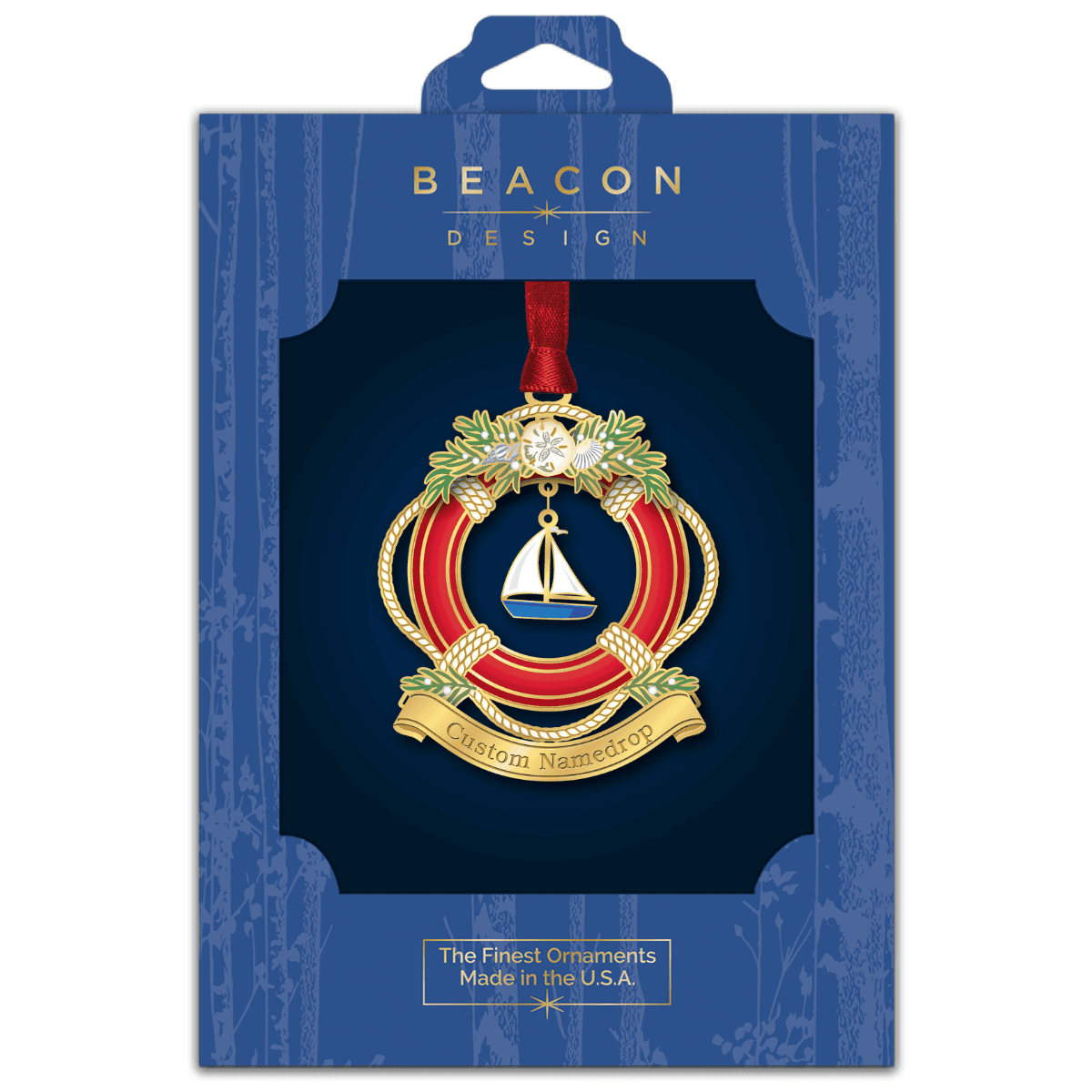 Custom namedrop ornament featuring a nautical life preserver decorated with evergreen branches, seashells, and a sailboat centerpiece, displayed in Beacon Design retail packaging