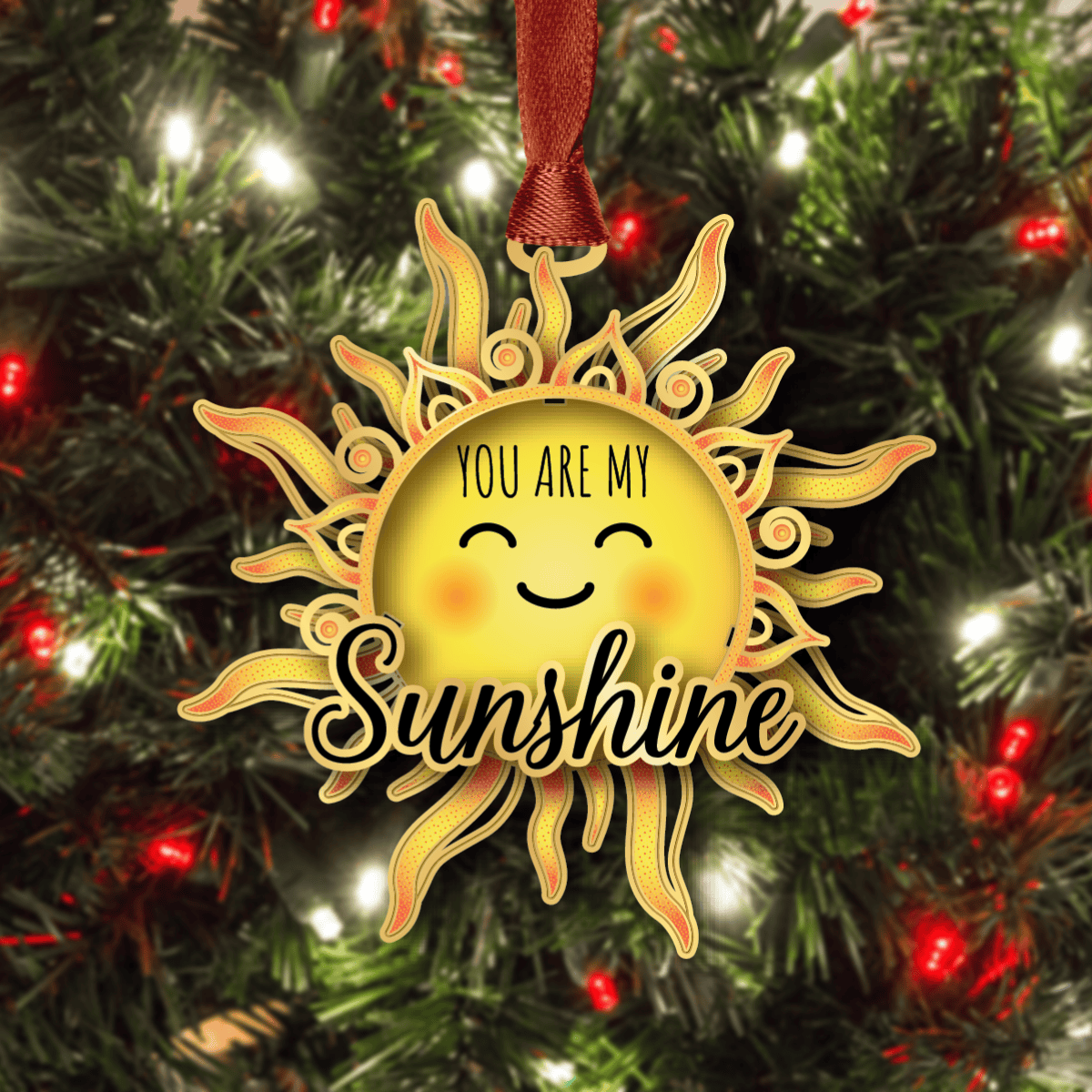 Ornament featuring a smiling sun with decorative rays and the message “You Are My Sunshine,” displayed on a decorated Christmas tree