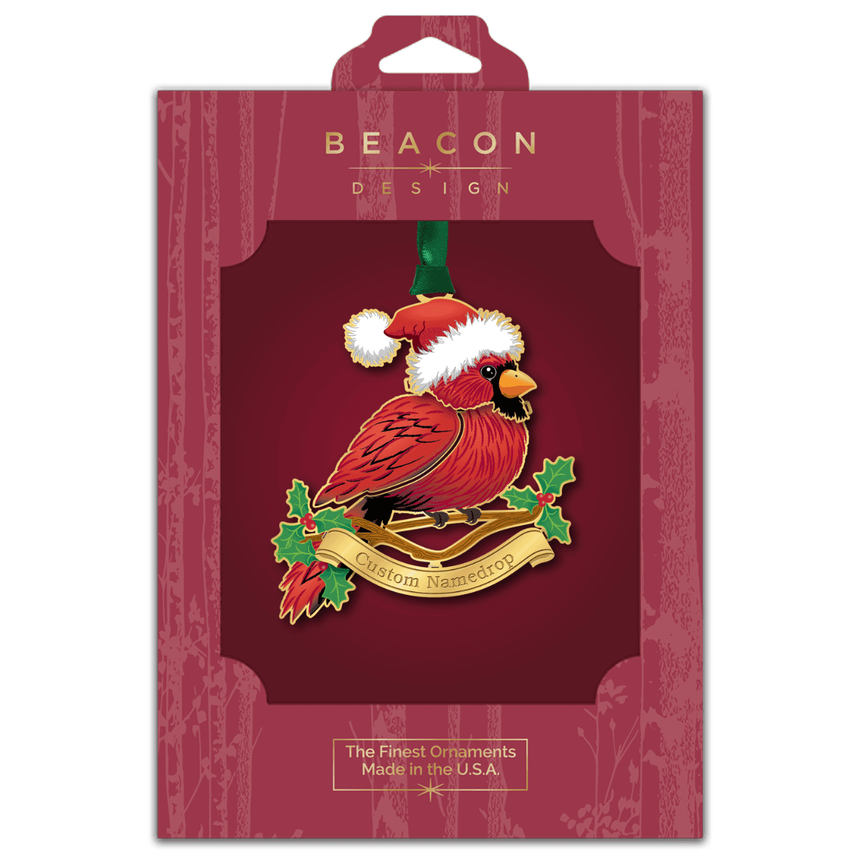 Custom namedrop ornament featuring a red cardinal wearing a Santa hat, perched on a branch with holly leaves and berries, displayed in Beacon Design retail packaging