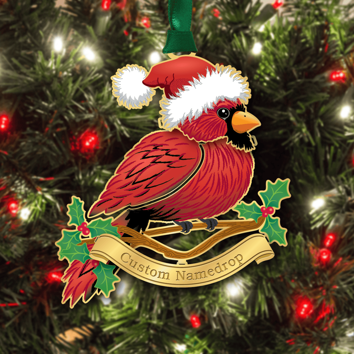 Custom namedrop ornament featuring a red cardinal wearing a Santa hat, perched on a branch with holly leaves and berries, displayed on a decorated Christmas tree