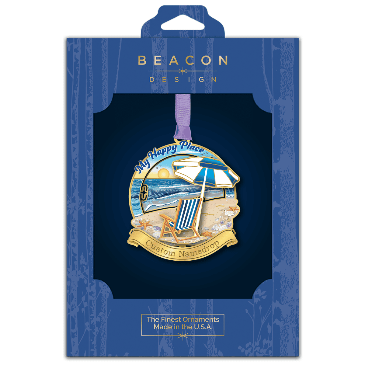 Custom namedrop ornament featuring a beach scene with a striped chair and umbrella overlooking the ocean at sunset, with the phrase “My Happy Place,” displayed in Beacon Design retail packaging