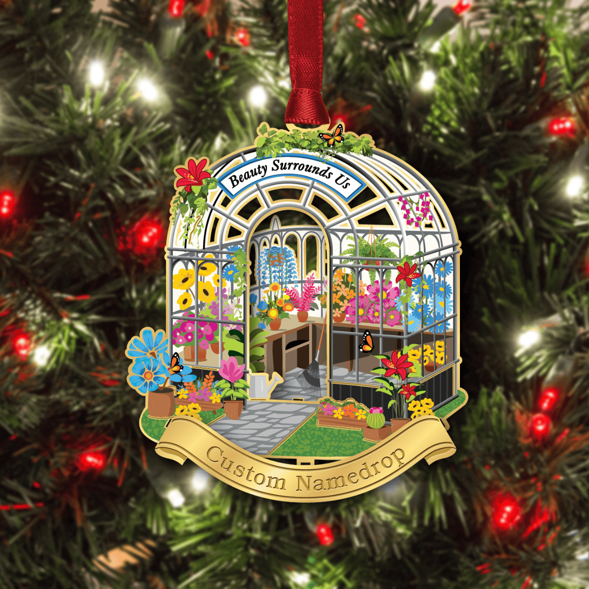 Custom namedrop ornament featuring a detailed greenhouse filled with colorful flowers, plants, and butterflies, displayed on a decorated Christmas tree