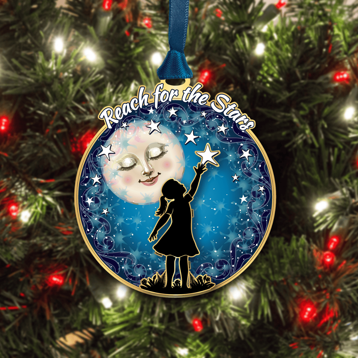Ornament featuring a child reaching toward a star under a night sky with “Reach for the Stars” text, displayed on a decorated Christmas tree