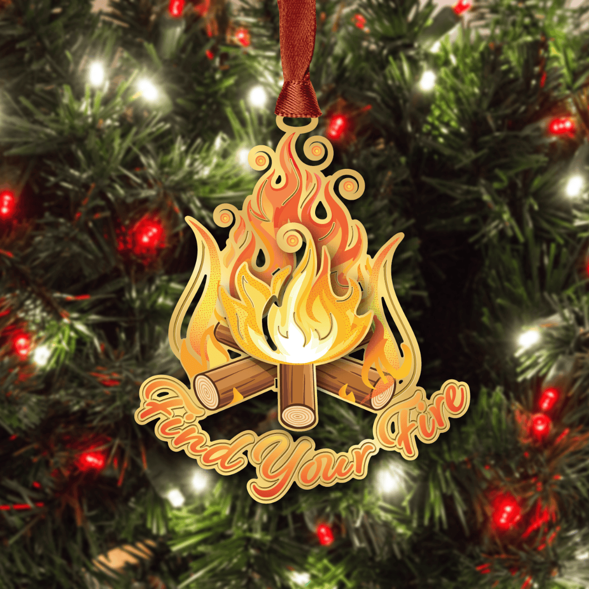 Ornament featuring a stylized campfire with flames and logs and “Find Your Fire” text displayed on a decorated Christmas tree
